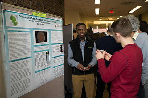 Two students discuss the poster for a poster session presentation