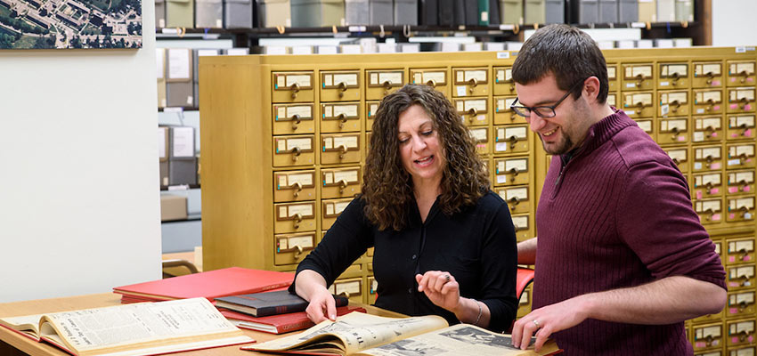 History graduate assistant Jon Herr and faculty member currently teaching a graduate course Laura Gathagan looking at the university archives