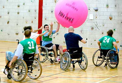 Group in wheelchairs playing with giant ball