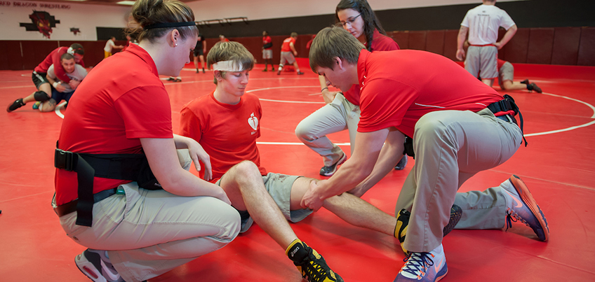 Athletic training students working with a Cortland wrestler