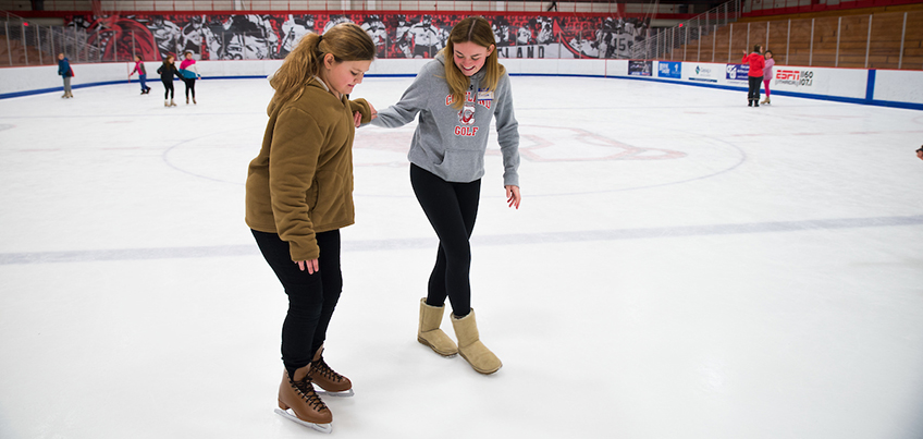 Student helping a local youth skate at Girls Night Out