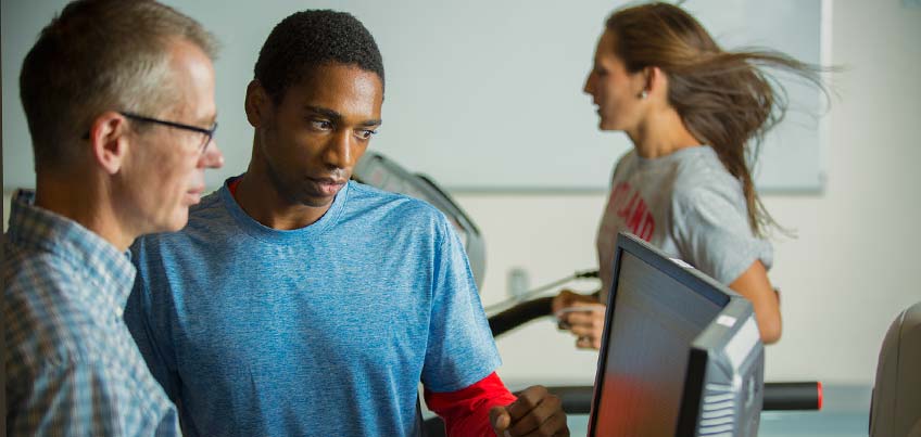Student and professor evaluating another student's treadmill activity