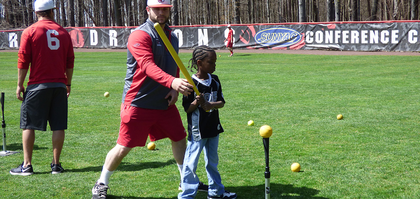 Baseball student-athlete working with a child at a youth clinic