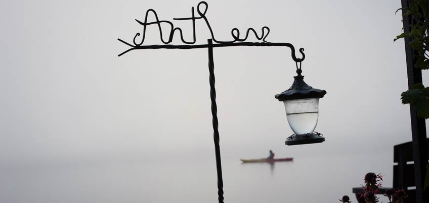 Antler's sign and hummingbird feeder and kayaker on a foggy morning