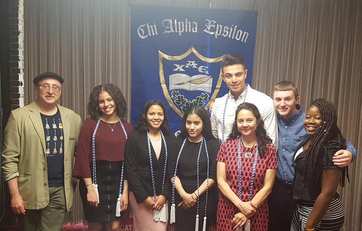 Group of students posing in front of a Chi Alpha Epsilon banner 
