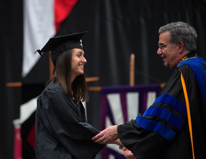 Student sharking President Bitterbaum's hand at graduation