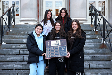 Delta Phi Epsilon holds their Greek community plaque.