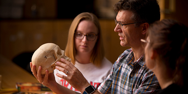 Professor Kent Johnson showing skull remains to students