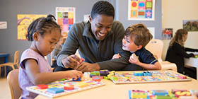 student teacher with young children working on puzzels at a table