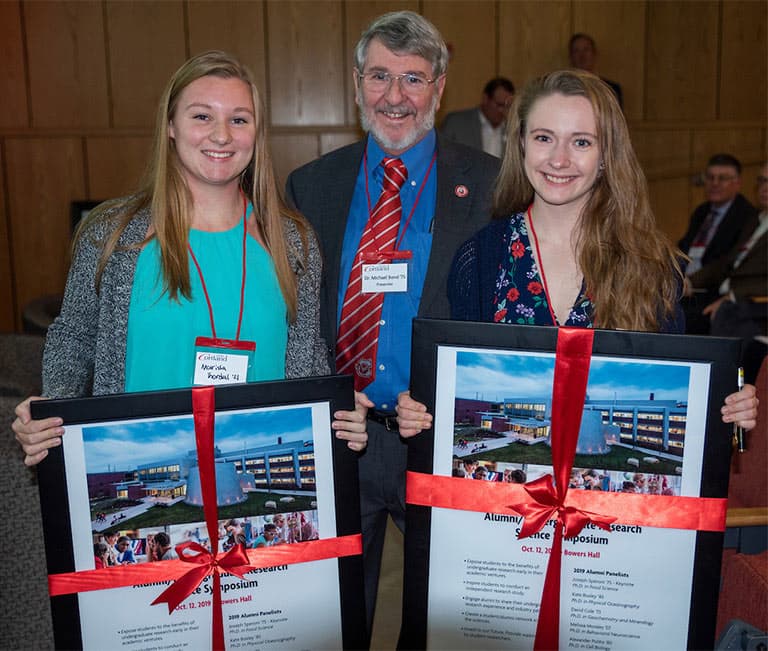 Bond with two students holding Science Symposium posters