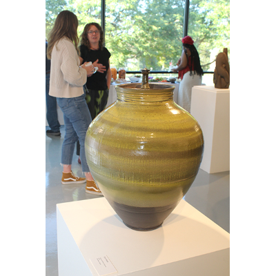 Behind an  Errol Willett vase, visitors mingle at the opening reception.