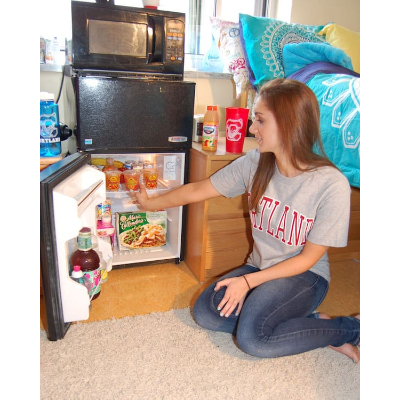 Student looking in her mini refrigerator in her dorm room