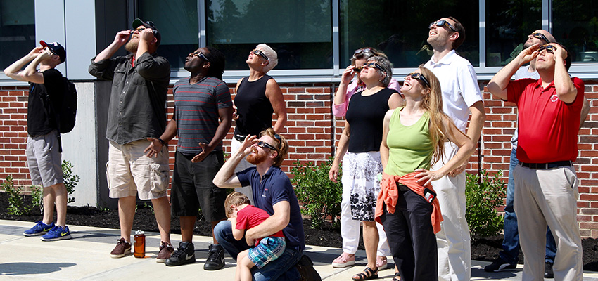 Crowd of 12 people looks up at an eclipse event outside Bowers Hall in on Aug. 21, 2017