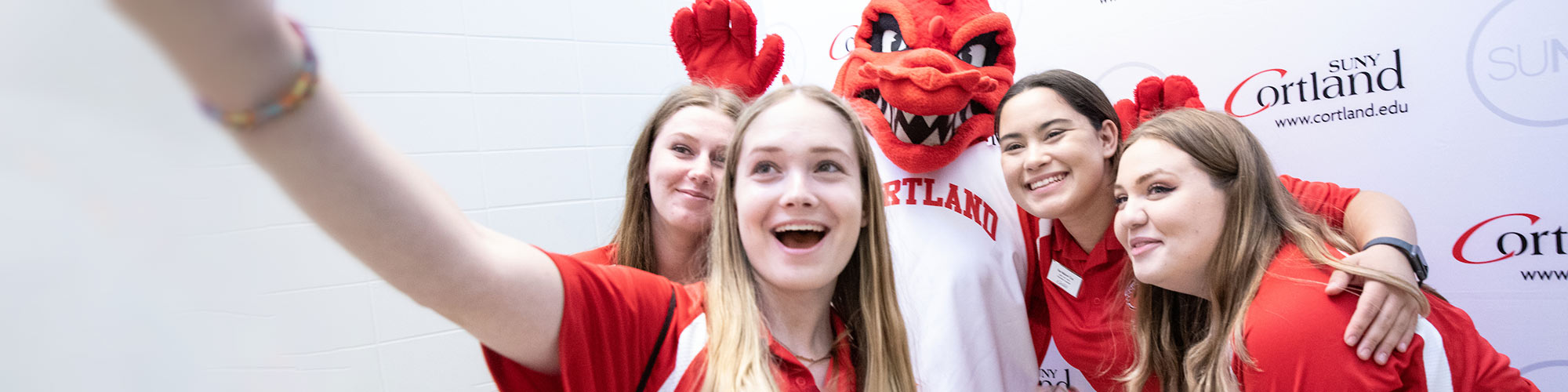 Four Orientation assistants take a selfie with Blaze the red dragon mascot