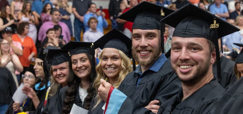 graduate students smiling in alumni arena at 2025 commencement