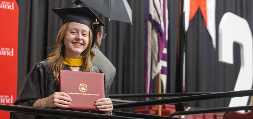 2025 graduate student walking off stage with diploma cover