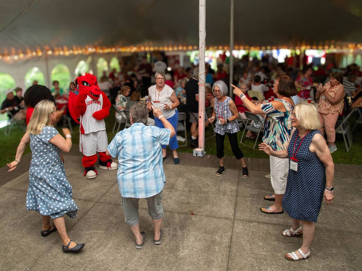 Alumni and Blaze dancing under a tent during Reunion