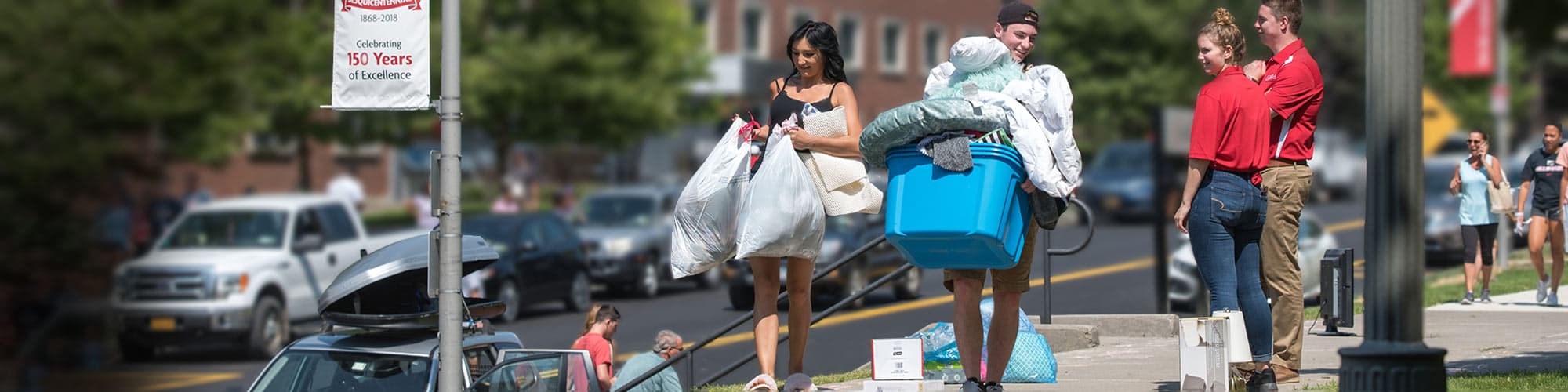 Students carrying bags, totes and belongings into residence hall