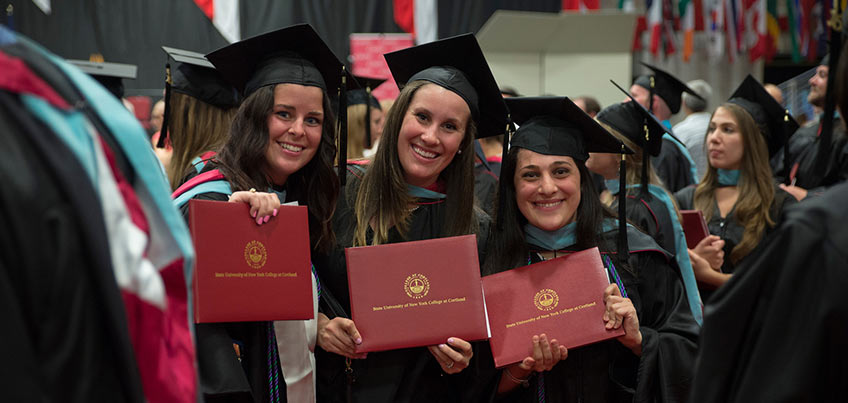 Graduate students holding their diplomas after commencement