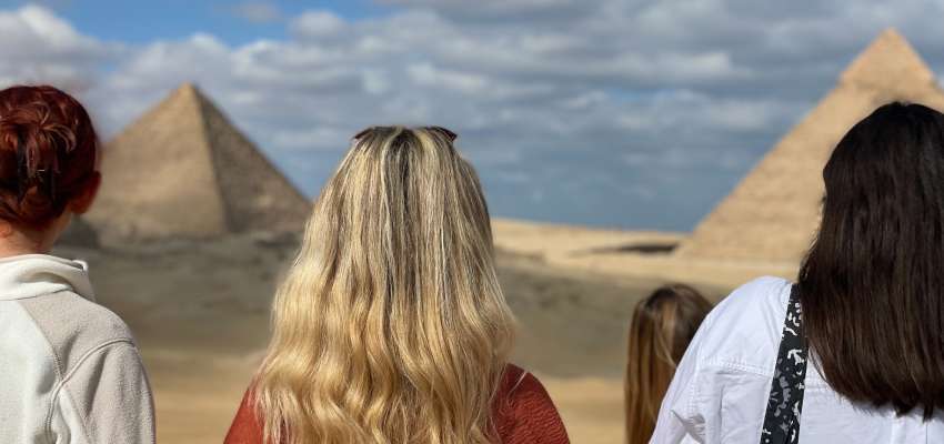 Students with their backs turned while looking at the pyramids at Giza in Egypt