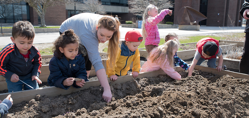 Child Care Center students dig in the dirt outside Cornish Hall