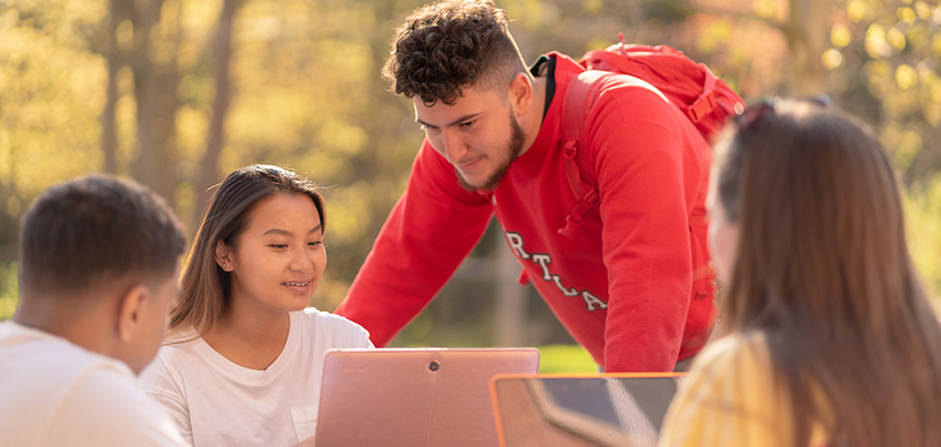 Students working together outdoors on a computer