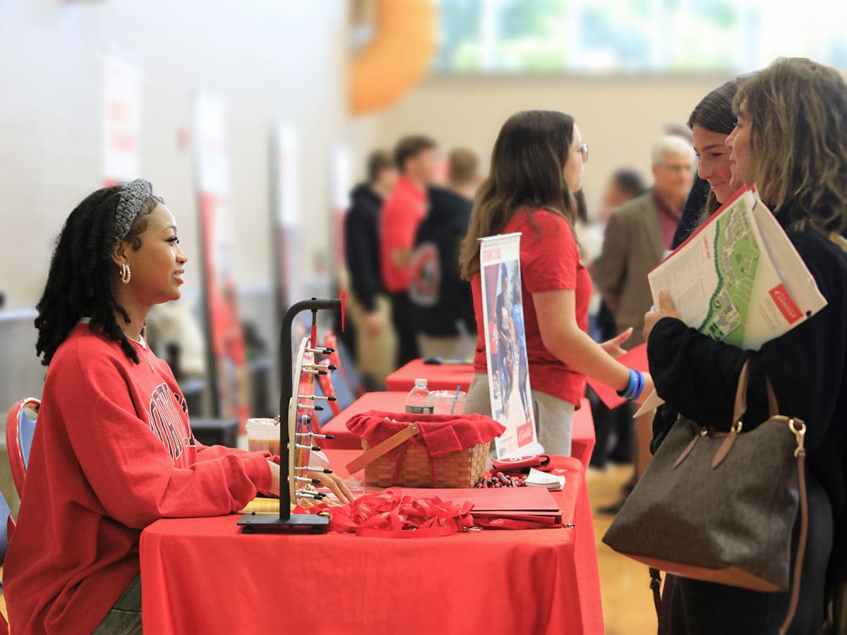 staff member talking with perspective students and their families at Open House