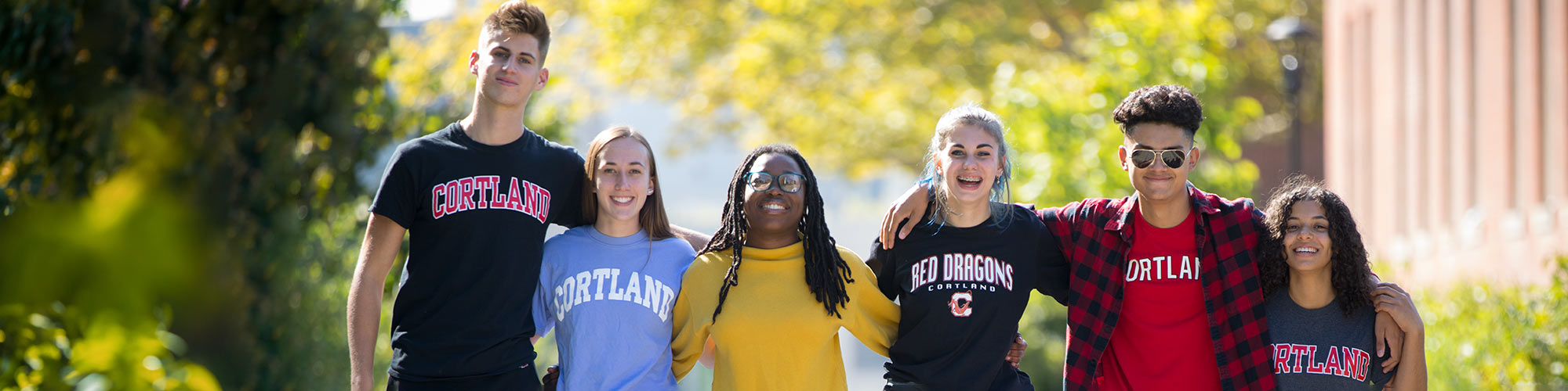 Six students wearing Cortland shirts walking with arms around each other