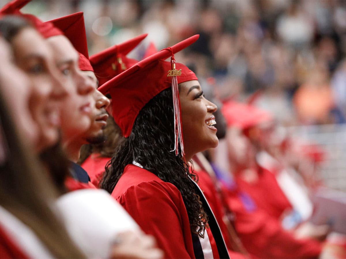 Graduates wearing caps excitedly looking at the stage