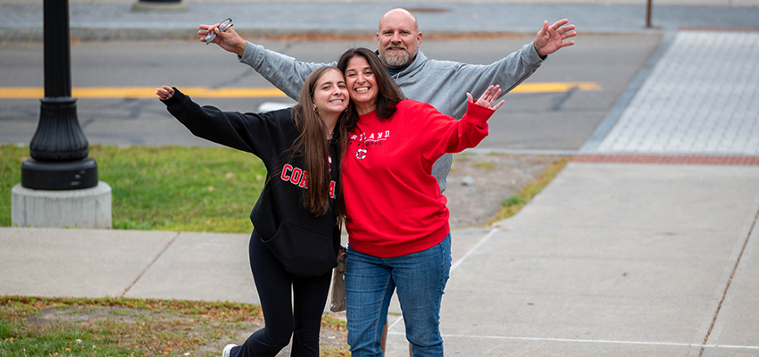 Family embraces for the camera with smiles and arms streatched wide