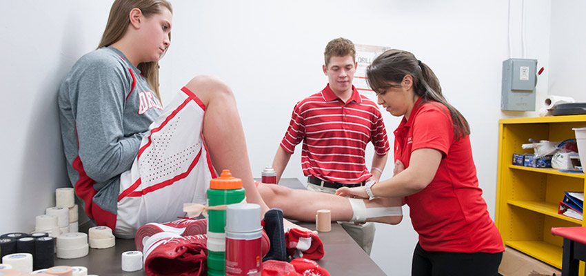 An athletic trainer tapes the ankle of a basketball player