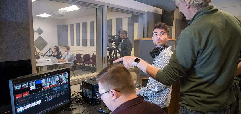Students working in control room with professor