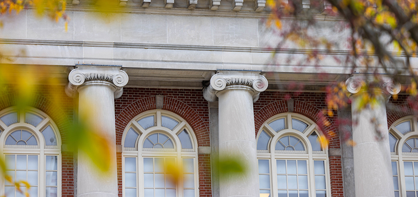 Close up of Old Main columns through autumn leaves.