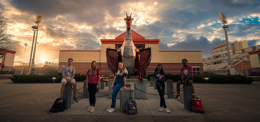 Students posing in the evening with the red dragon statue in the background