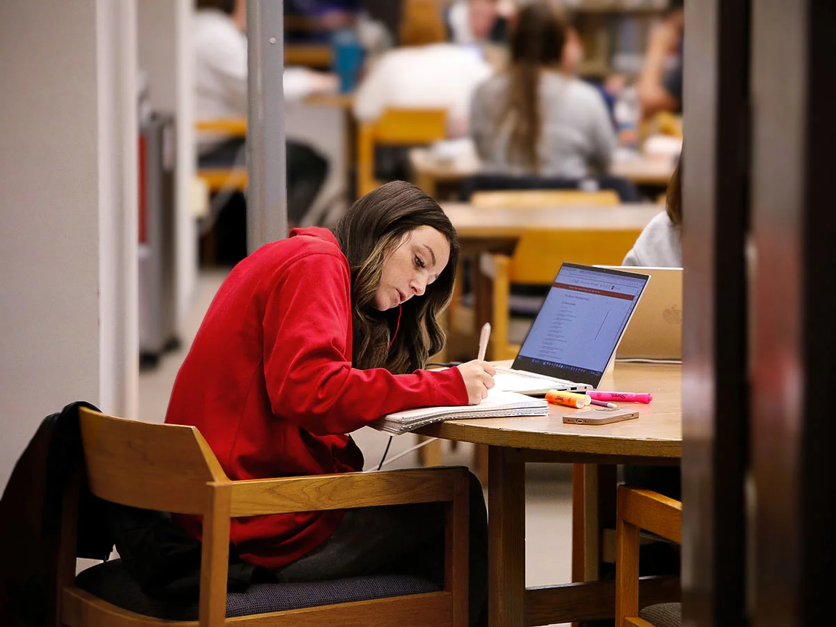 Student writing in notebook in the library