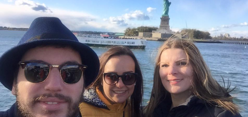 Three students standing in front of the Statue of Liberty