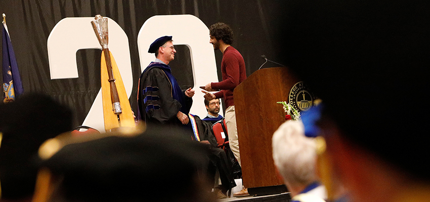 Student shakes hands and receives an award from Professor Kevin Sheets of the History Department