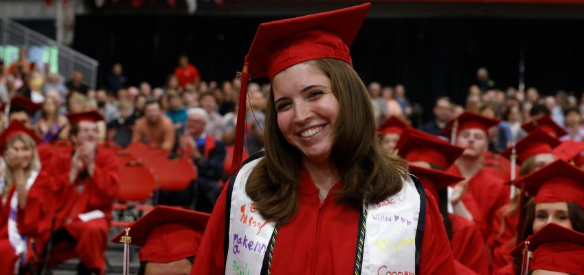 smiling student standing in regalia at 2025 undergraduate commencement