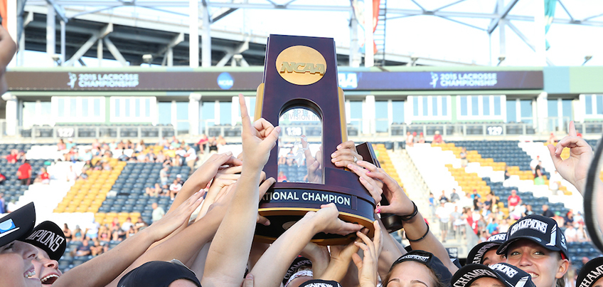Cortland student-athletes hold up the national champion trophy in women's lacrosse