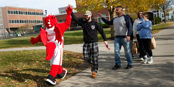 blaze giving a high five to a prospective student and parent