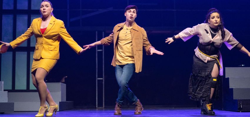 Three dancers on a stage; two women with a man in the middle.