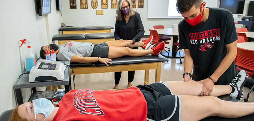 Student and faculty member practice hands-on training in athletic training classroom