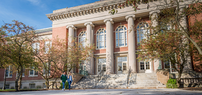 A Photo of Old Main's steps on a sunny day with two students walking in the foreground.