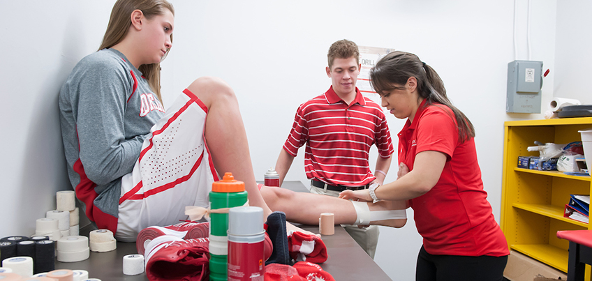 Athletic trainer tapes the ankle of a basketball player