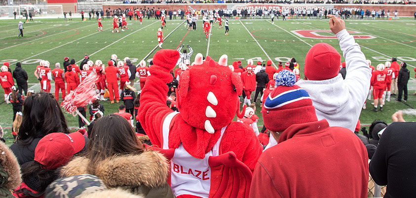 Blaze joins the crowd to cheer on the Red Dragons at a football game