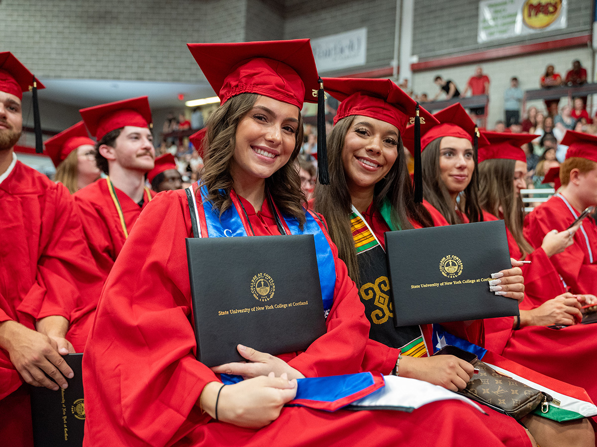2025 graduates showing off diploma covers and smiling