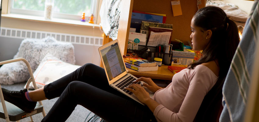 student leaning back in her chair while working on her laptop