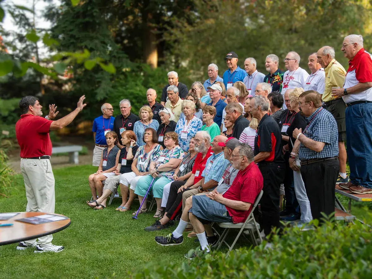 A photographer directs a alumni for a group photo