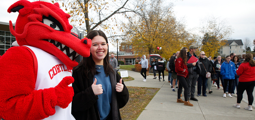 Blaze poses with prospective student on campus during Fall open house with a tour behind them.