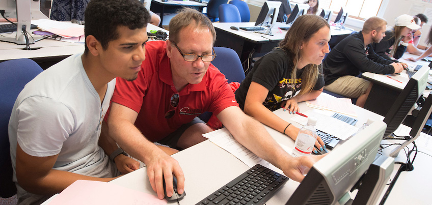 Physical Education Professor John Foley advises a transfer student at a computer at Orientation